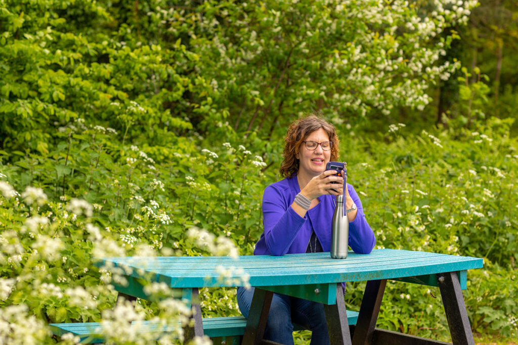 Clare Cogan in a natural setting scrolling through her mobile phone to reflect the content of the blog post around tracking teenagers